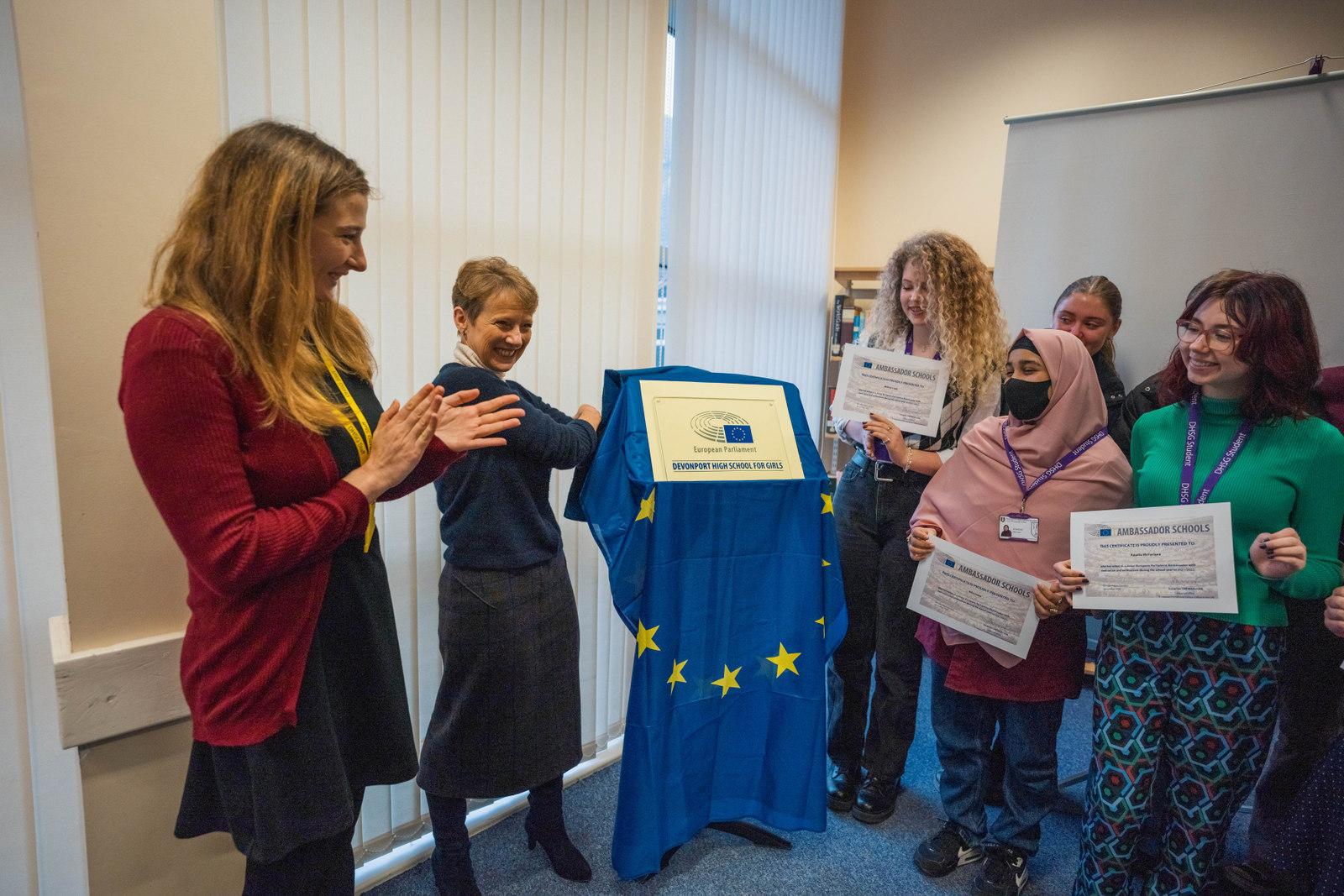 Unveiling of European Parliament Ambassador Schools plaque at DHSG. Teacher, MEP and students smiling.